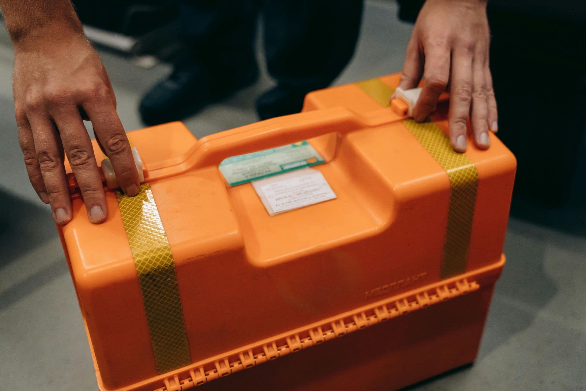 Hands securing the latch of a hard-shell medical transport case